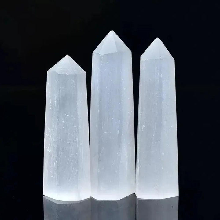 Three luminous white Selenite hexagonal obelisk wands for cleansing energy, meditation, and crown chakra alignment.