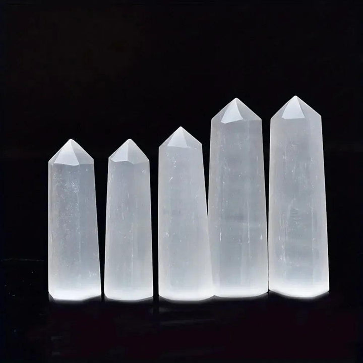 Luminous white Selenite crystal hexagonal towers for meditation and cleansing, standing in a row against a black background.