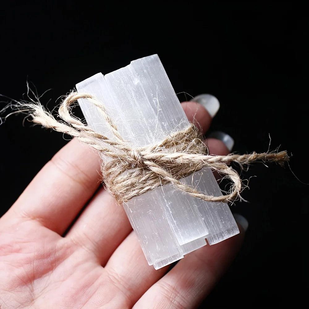 Hand holding a bundle of natural white Selenite Crystal Wands, raw gypsum sticks tied with twine.