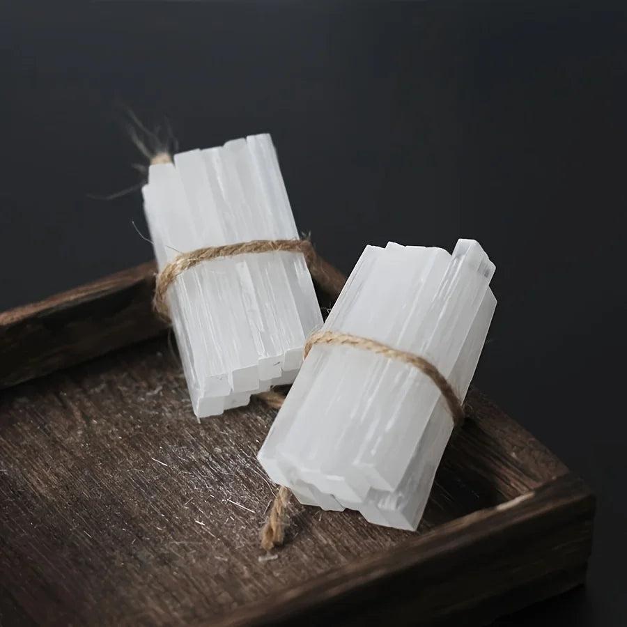 Two bundles of raw white Selenite crystal wands, tied with twine, on a dark wooden tray.