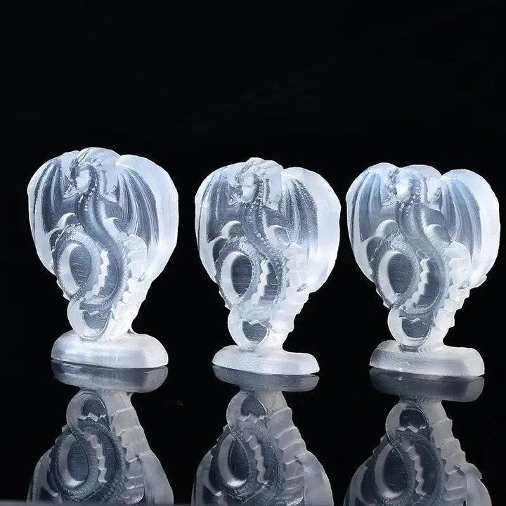 Three luminous white selenite fire dragon carvings from Crystal Destiny, showcasing pearly translucence.