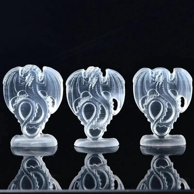 Three luminous white selenite fire dragon carvings from Crystal Destiny, reflecting on a dark surface.