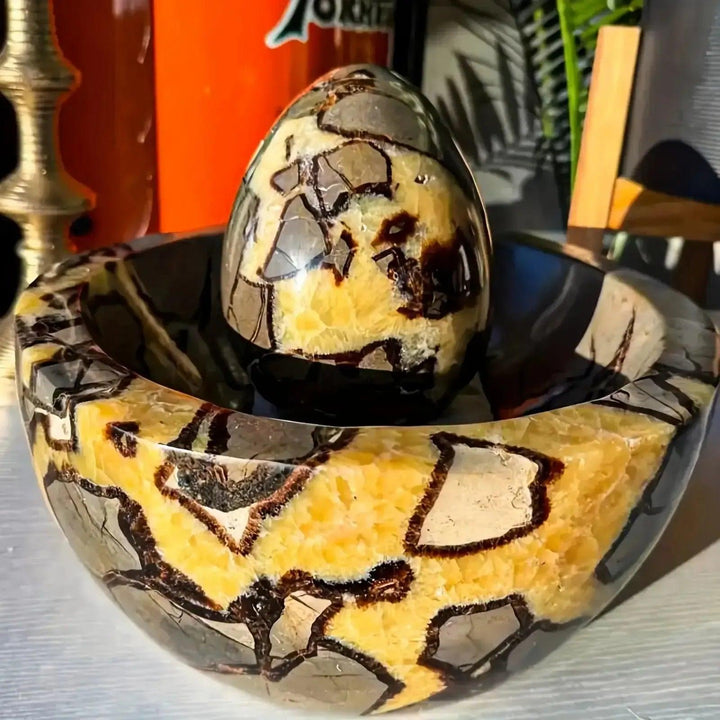 Polished Septarian Dragon Stone egg with golden calcite, brown aragonite, and grey limestone, resting in a matching bowl.