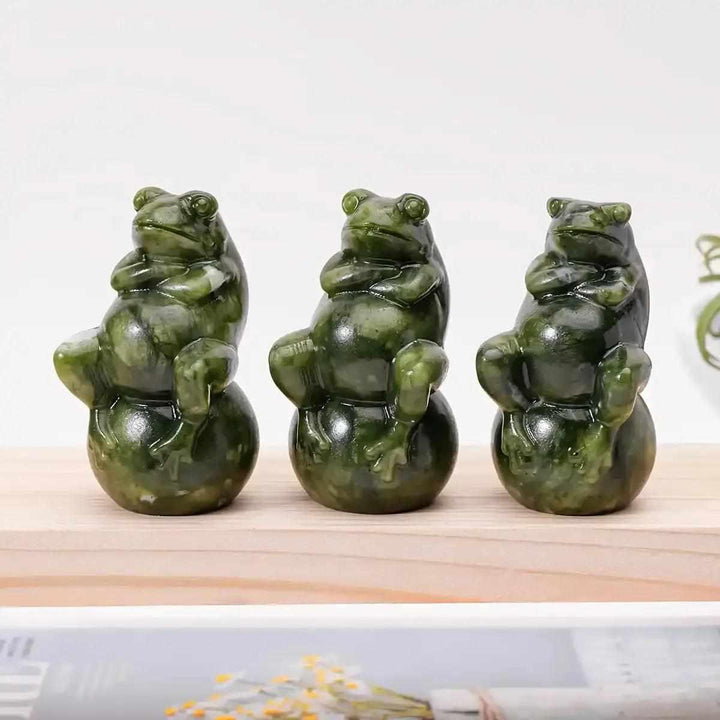Three polished Serpentine Jade frog carvings seated on round balls, featuring mottled forest and olive green tones.