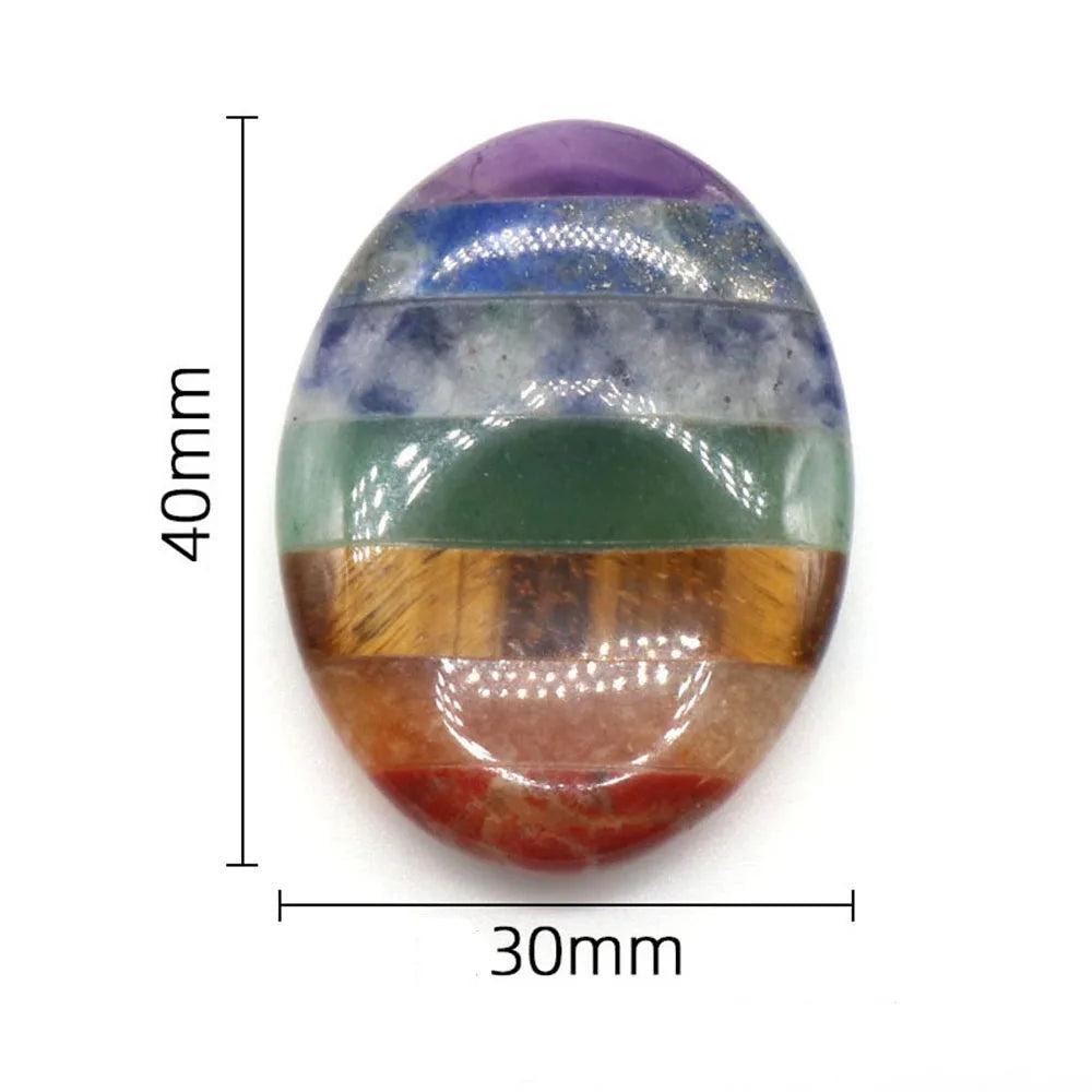 Polished 30x40mm oval Seven Chakra Crystal Fused palm stone with seven vibrant layers for energy healing.