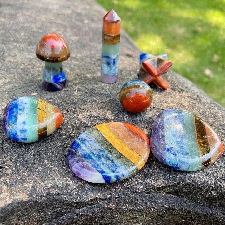 Seven Chakra Crystal Fused Polished Stone Collection, featuring vibrant layered crystals in various shapes like spheres, wands, and palm stones.