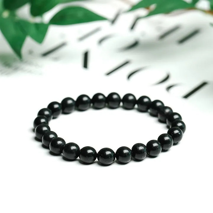 Shungite Bead Bracelet: matte black round beads with green leaves in the background
