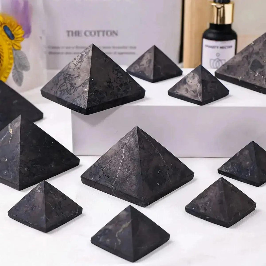 Polished black shungite crystal pyramids from Crystal Destiny, showcasing natural texture and geometric design.