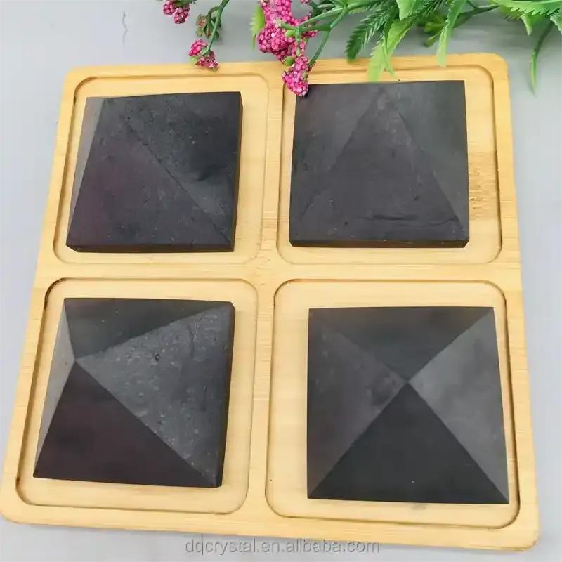 Satin black Shungite crystal pyramids on a wooden tray for grounding, protection, and sacred geometry meditation.