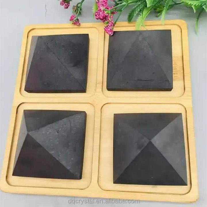 Satin black Shungite crystal pyramids on a wooden tray for grounding, protection, and sacred geometry meditation.