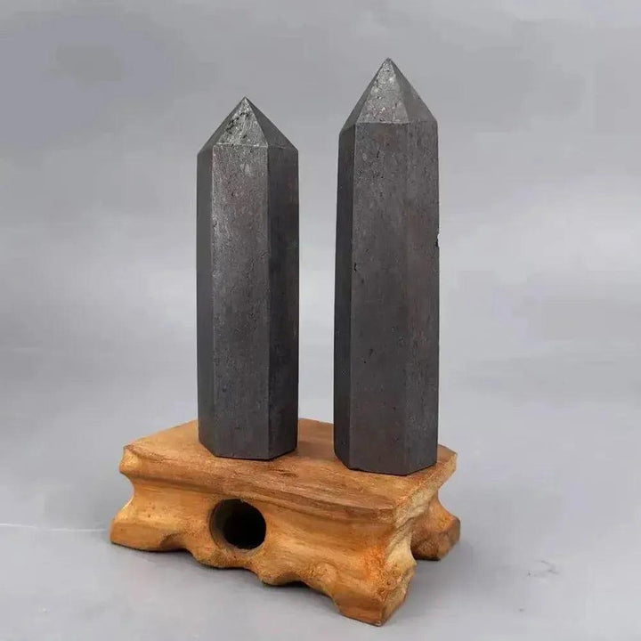 Two dark gray Shungite Crystal Towers on a light brown wooden stand from Crystal Destiny.