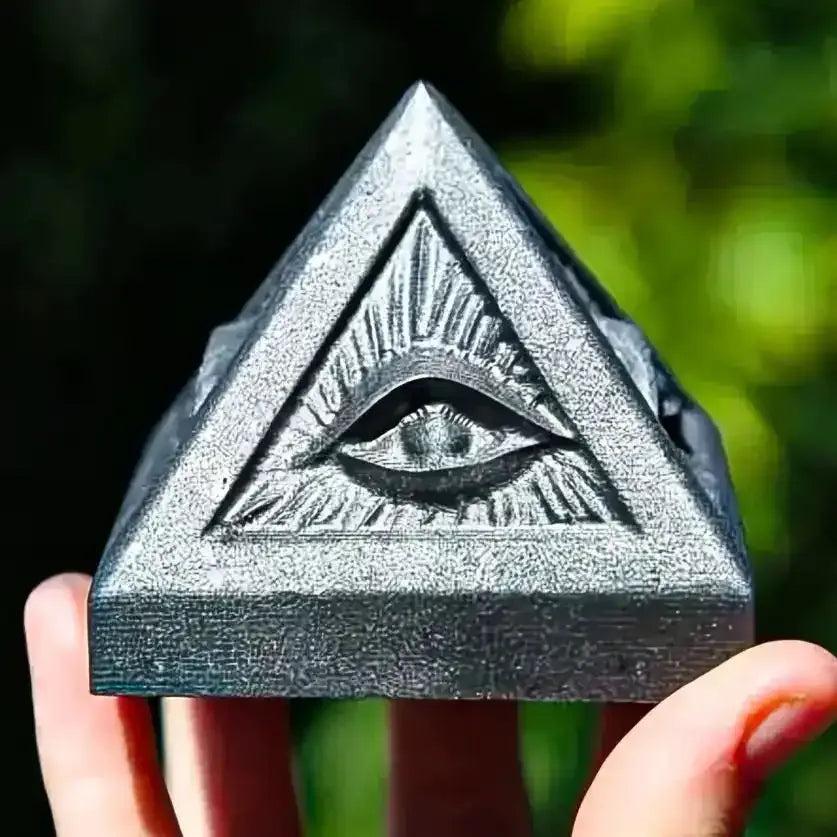 Hand-polished satin black Shungite pyramid featuring an engraved Eye of Providence for grounding and Root chakra protection.