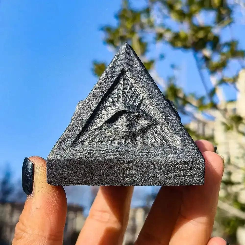 Hand-polished satin black Shungite pyramid featuring an etched All-Seeing Eye for grounding and spiritual protection.
