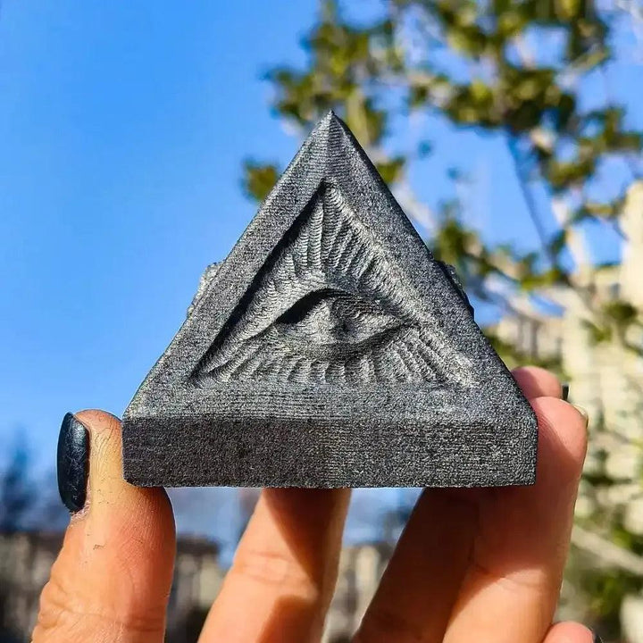 Hand-polished satin black Shungite pyramid featuring an etched All-Seeing Eye for grounding and spiritual protection.
