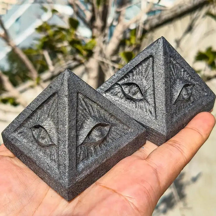 Hand-polished Shungite pyramid with an engraved eye design, perfect for Root chakra grounding and protective energy.