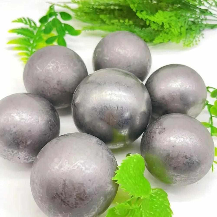 Polished black Shungite spheres with a metallic sheen, perfect for grounding, protection, and root chakra balancing.