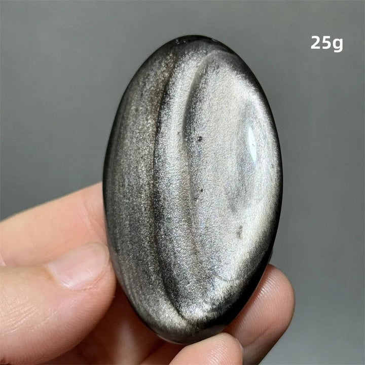 Polished 25g Silver Sheen Obsidian palm stone with a glossy black surface and shimmering silver light reflection.