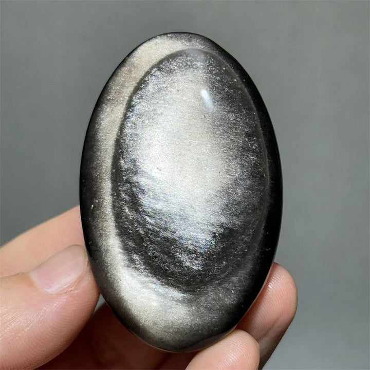 Polished Silver Sheen Obsidian palm stone with a glossy black surface and radiant silver shimmer for grounding and insight.