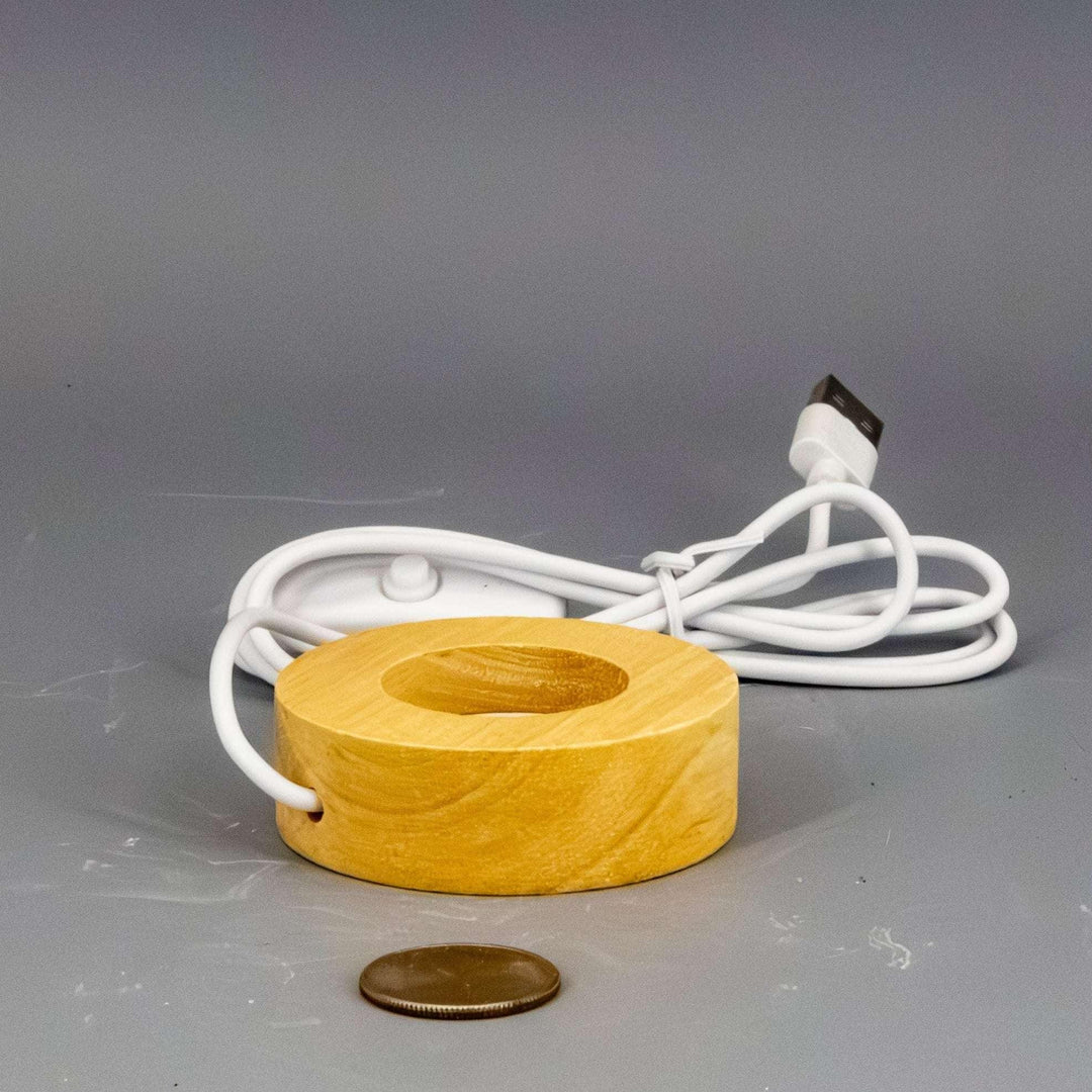 Small 7 Color Selectable LED Light Base, natural wood, round, with white USB cable, next to a coin.