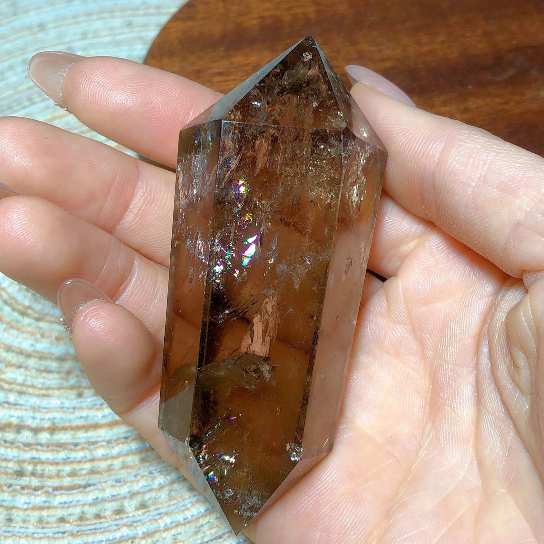 Smoky quartz double point crystal with natural rainbow flash inclusions held in hand for meditation and energy work.