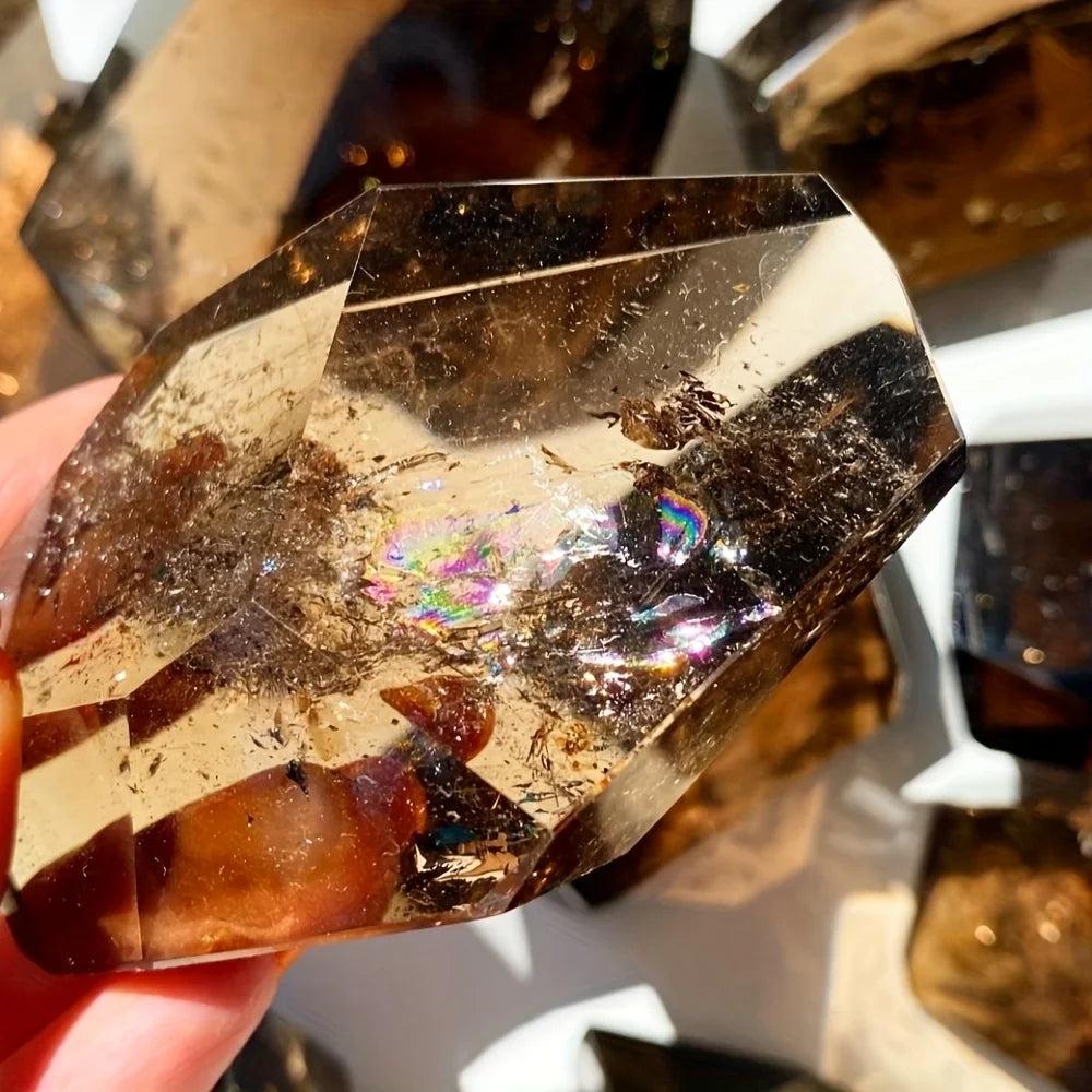 Polished Smoky Quartz freeform crystal, translucent brown with iridescent rainbow inclusions, held in hand.