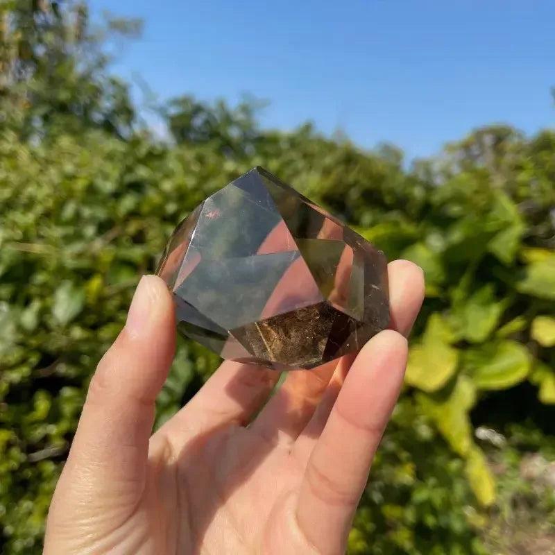 Polished dark brown Smoky Quartz freeform crystal, held outdoors by Crystal Destiny, for grounding.