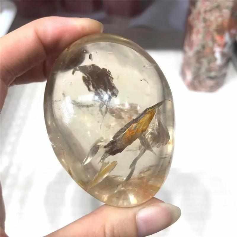 Smooth, translucent smoky quartz palm stone with natural brown inclusions, perfect for grounding and meditation.