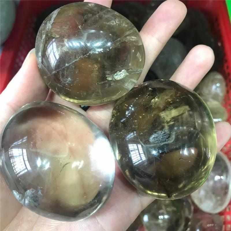 Smooth, translucent smoky quartz palm stones in brown and gray, perfect for grounding and root chakra meditation.