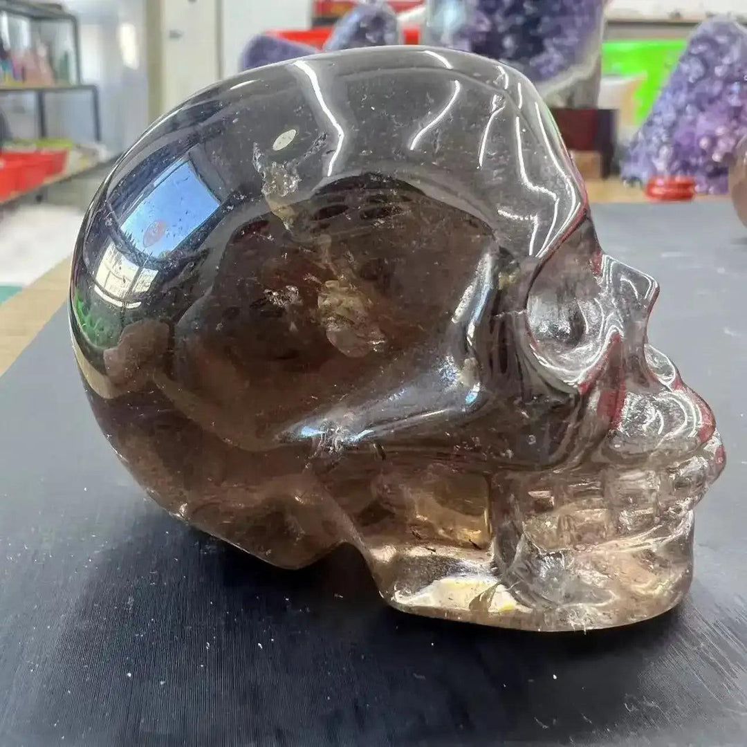 Polished smoky quartz skull carving with translucent brown tones, perfect for grounding and root chakra meditation.