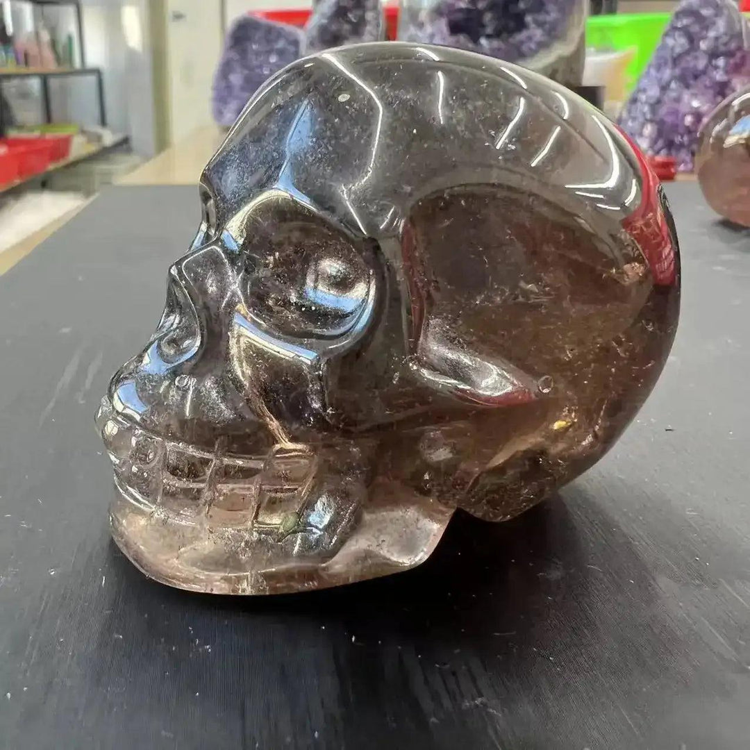 Polished smoky quartz skull carving with translucent brown tones, perfect for grounding and root chakra meditation.