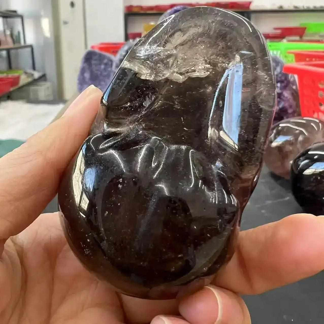 Hand-carved smoky quartz skull, a translucent, grounding crystal with polished curves for protection and wisdom.