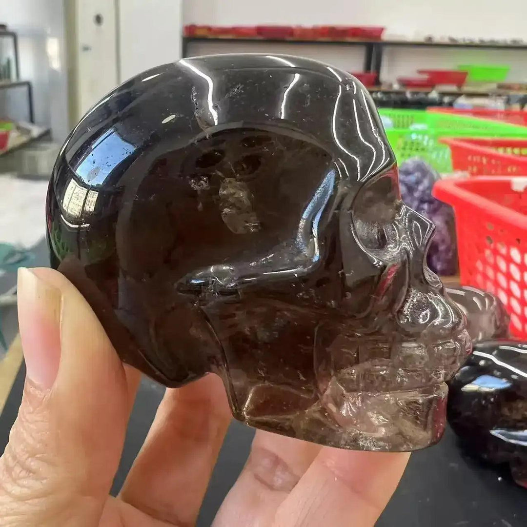 Hand-carved smoky quartz skull, a translucent grounding crystal with smooth, polished curves for wisdom and protection.