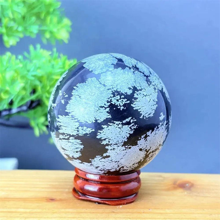 Snowflake Obsidian Sphere with White Snowflake Patterns. Deep black volcanic crystal for grounding and protection.