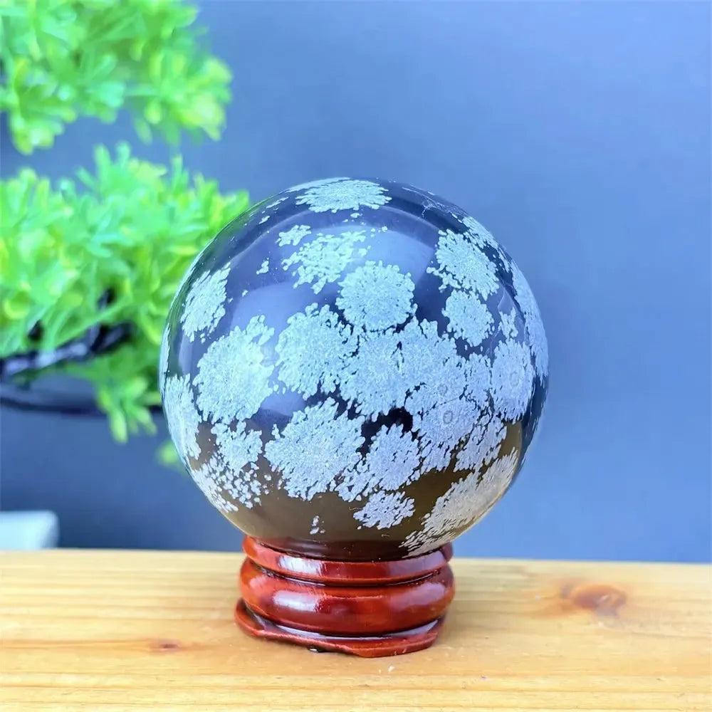 Snowflake Obsidian Sphere with White Snowflake Patterns. Polished black volcanic crystal for grounding and protection.