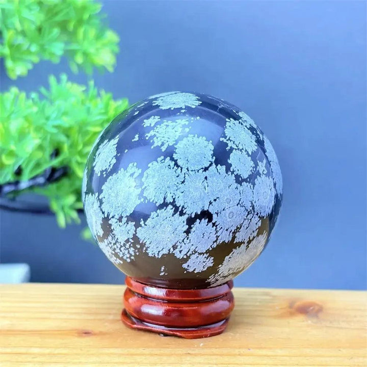 Snowflake Obsidian Sphere with White Snowflake Patterns. Polished black volcanic crystal for grounding and protection.