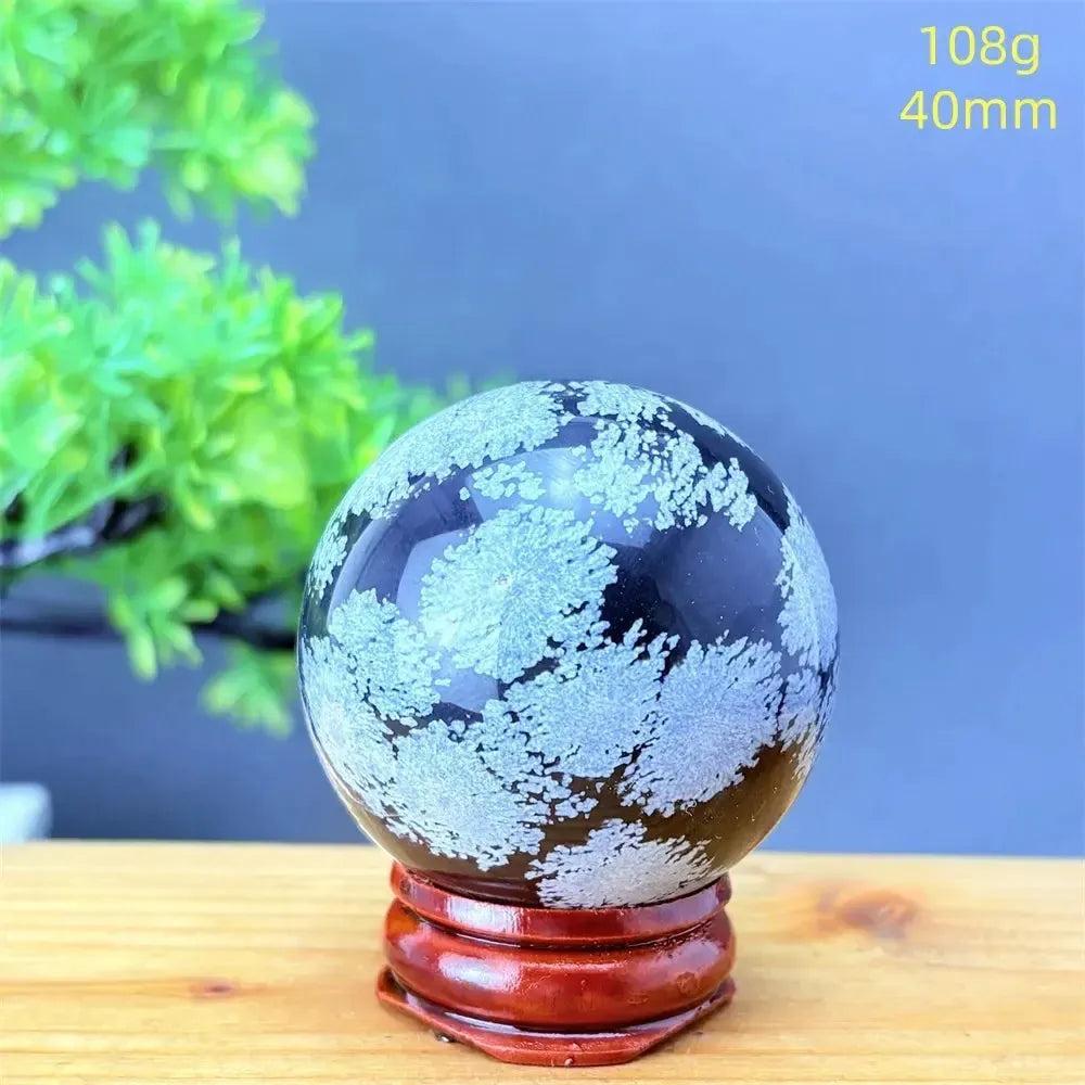 Snowflake Obsidian Sphere: Deep black crystal with delicate white snowflake patterns, promoting grounding and balance.