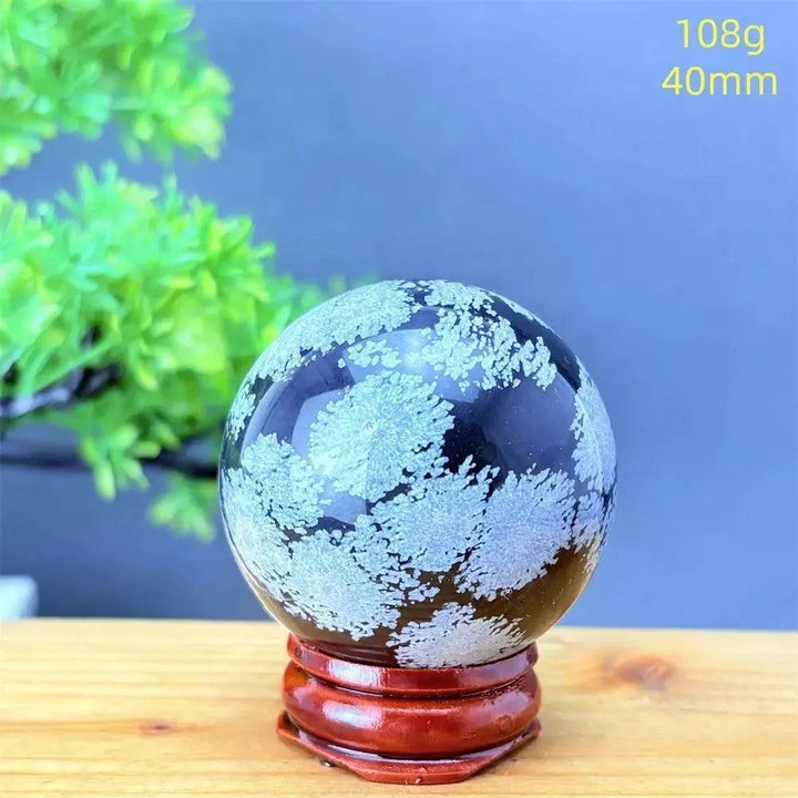 Snowflake Obsidian Sphere: Deep black crystal with delicate white snowflake patterns, promoting grounding and balance.