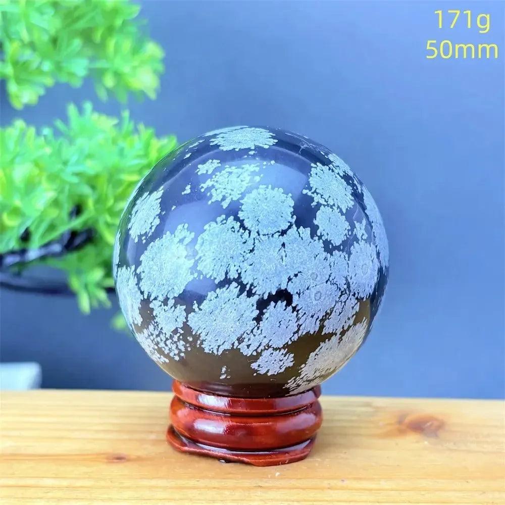 Snowflake Obsidian Sphere with White Snowflake Patterns. Deep black volcanic crystal for grounding and protection.