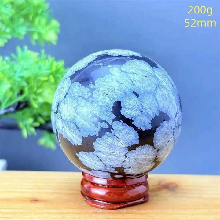 Snowflake Obsidian Sphere with White Snowflake Patterns. Polished black volcanic crystal for grounding and protection.