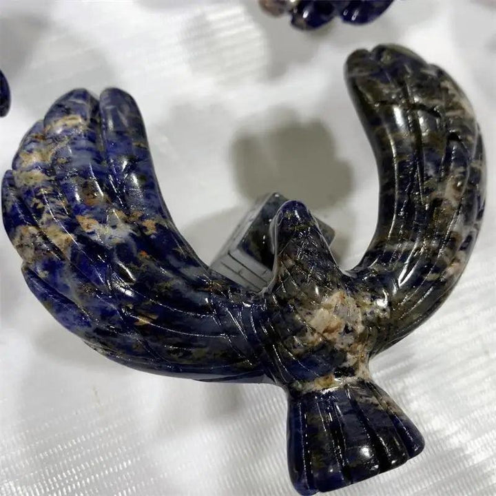 Polished sodalite crystal eagle statue with deep blue and white veining, balanced on a rotating pyramid base.