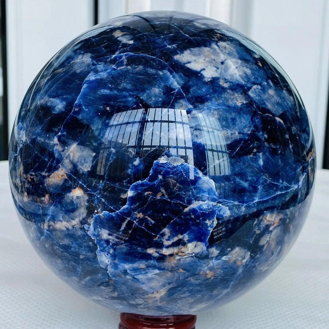 Polished Sodalite crystal sphere featuring deep blue hues and natural white mineral veining for Throat Chakra healing.