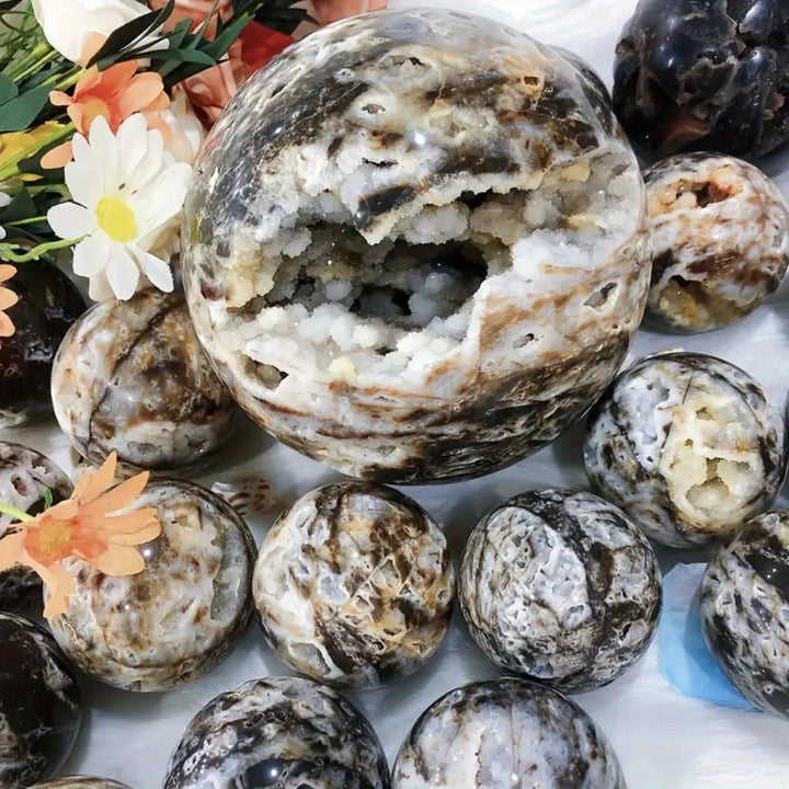Large gray and black Sphalerite crystal sphere with a sparkling geode cavity, surrounded by smaller matching spheres.