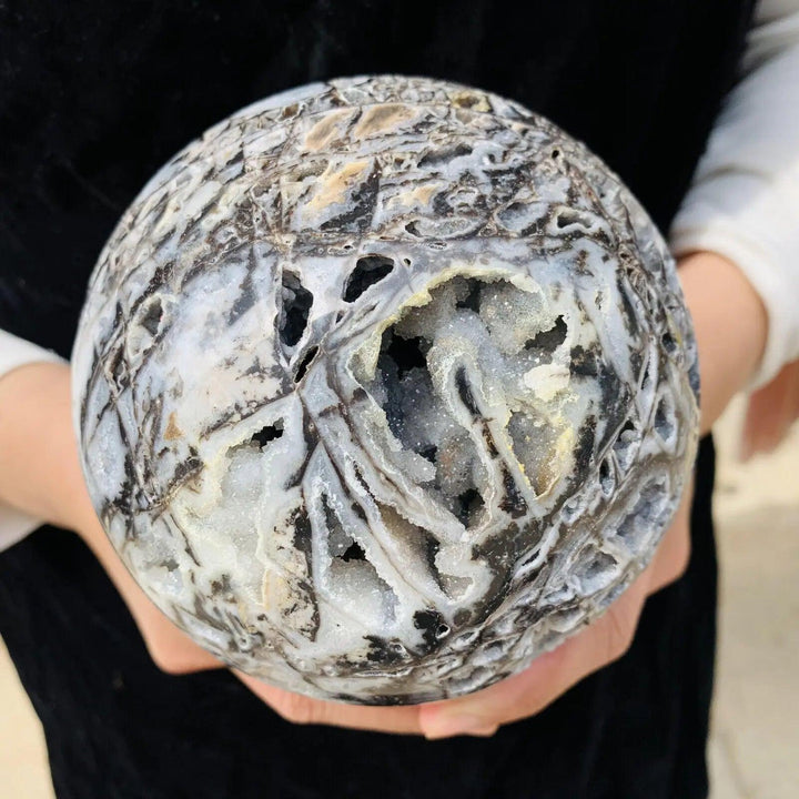 Sphalerite Crystal Sphere: Natural gray mineral ball with intricate patterns and sparkling geode pockets, held in hands.