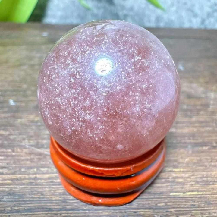 Polished 32mm Strawberry Quartz mini sphere featuring pink hues and white snowflake inclusions for heart chakra healing.