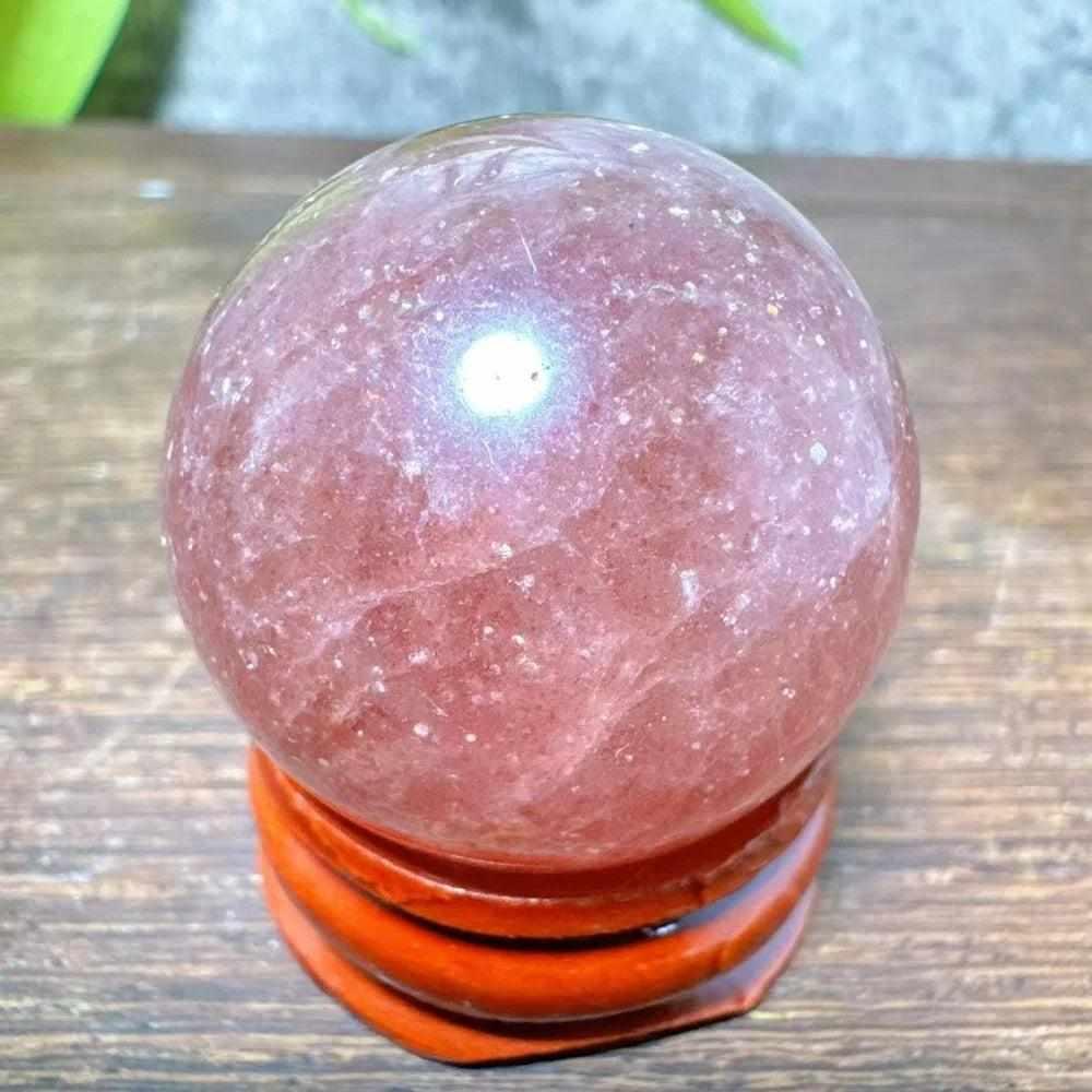 Polished 30mm Strawberry Quartz mini sphere featuring pink hues and white snowflake inclusions for heart chakra healing.