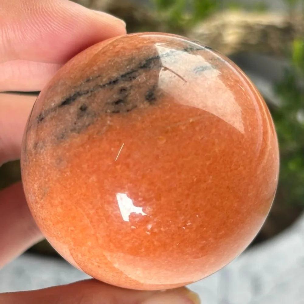 Polished Striped Sunstone sphere in warm orange with natural bands, perfect for boosting confidence and solar energy.