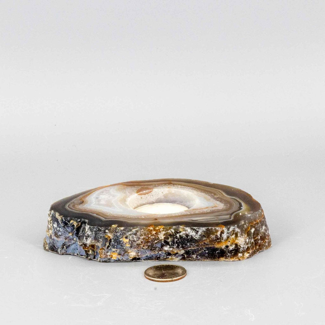 Polished brown and white Agate slice tea light candle holder with natural banding, a hollowed center, and rough edges.