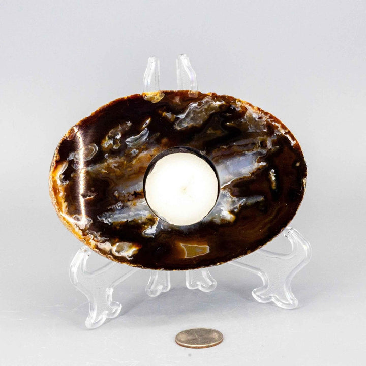 Polished, thick brown Agate slice tea light candle holder with natural banding, glowing with warm amber light.