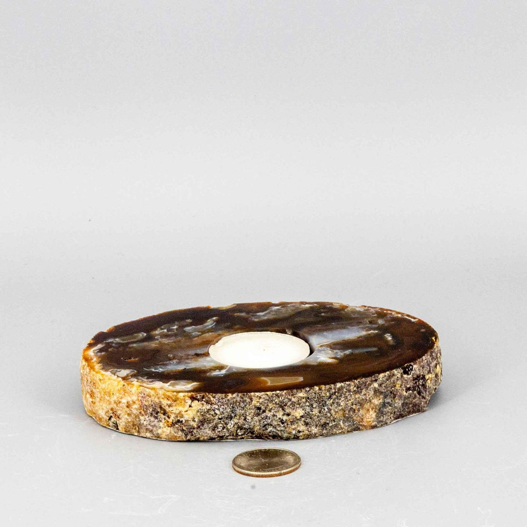 Thick, polished brown Agate slice tea light candle holder with natural banding and a rough edge, beside a US dime.