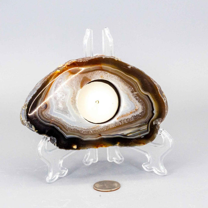 Polished brown and white Agate slice tea light candle holder on a stand, with a quarter for scale.